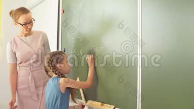 在教室里和老师一起上学。 黑板旁边的女孩<strong>展示</strong>她的家庭<strong>作业</strong>